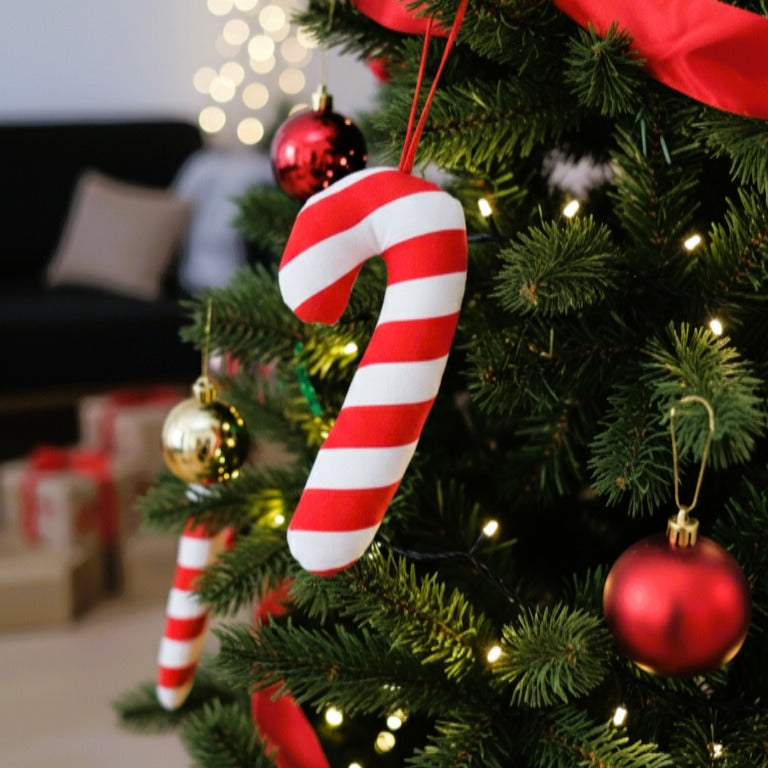 Μεγάλο υφασμάτινο στολίδι Candy Cane (μπαστουνάκι ζαχαρωτού) με κόκκινες και λευκές ρίγες, κρεμασμένο σε χριστουγεννιάτικο δέντρο.
